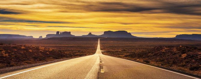Desert road leading to Monument Valley at sunset